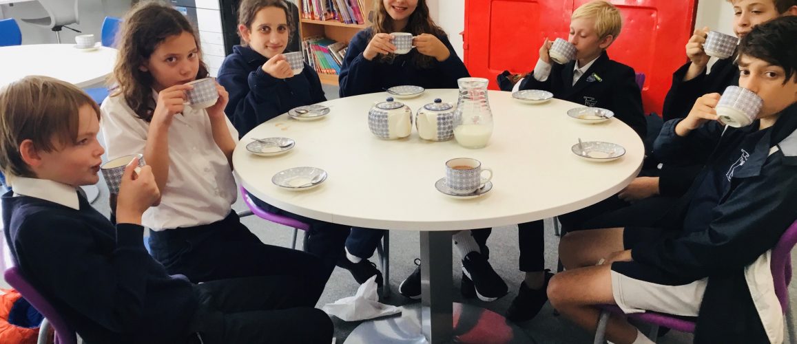 group of children sitting around a table drinking tea