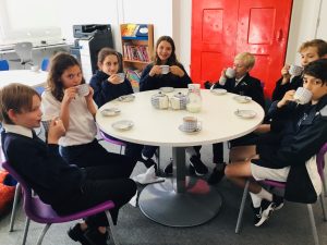 group of children sitting around a table drinking tea