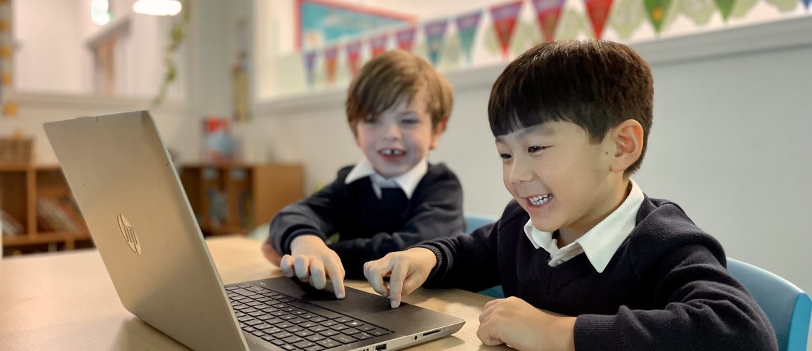 2 students clicking onto the laptop