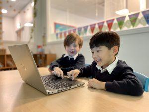 2 students clicking onto the laptop