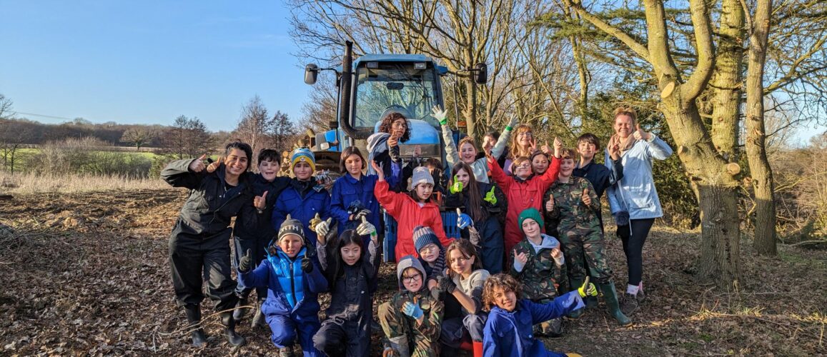 group of children with their thumbs up and a tractor in the background