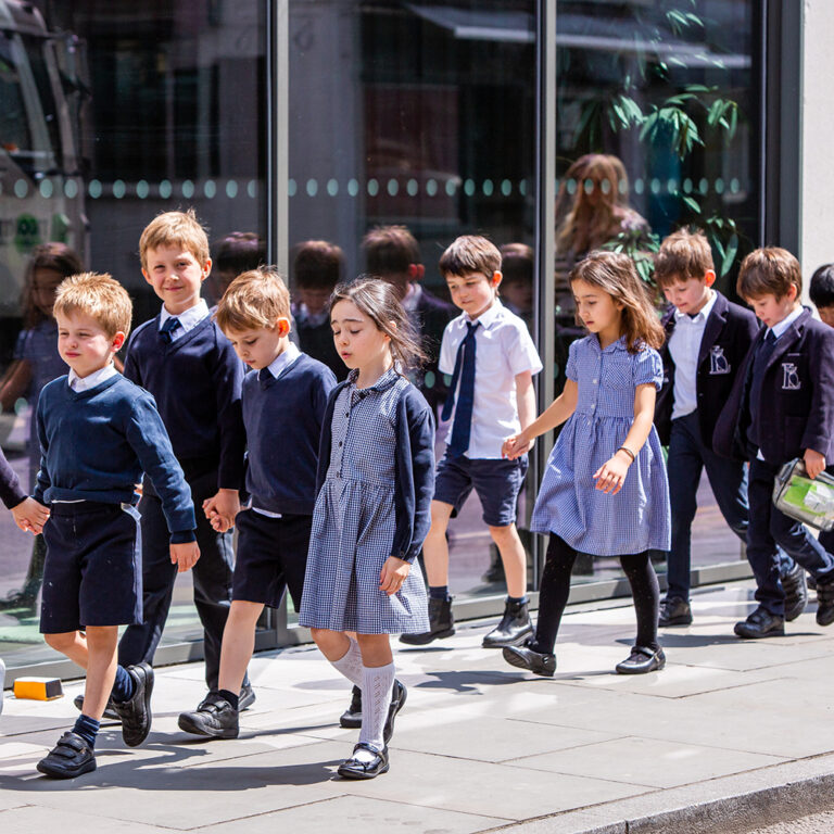students in pairs walking along the pavement