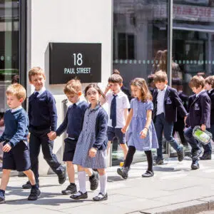 students in pairs walking along the pavement