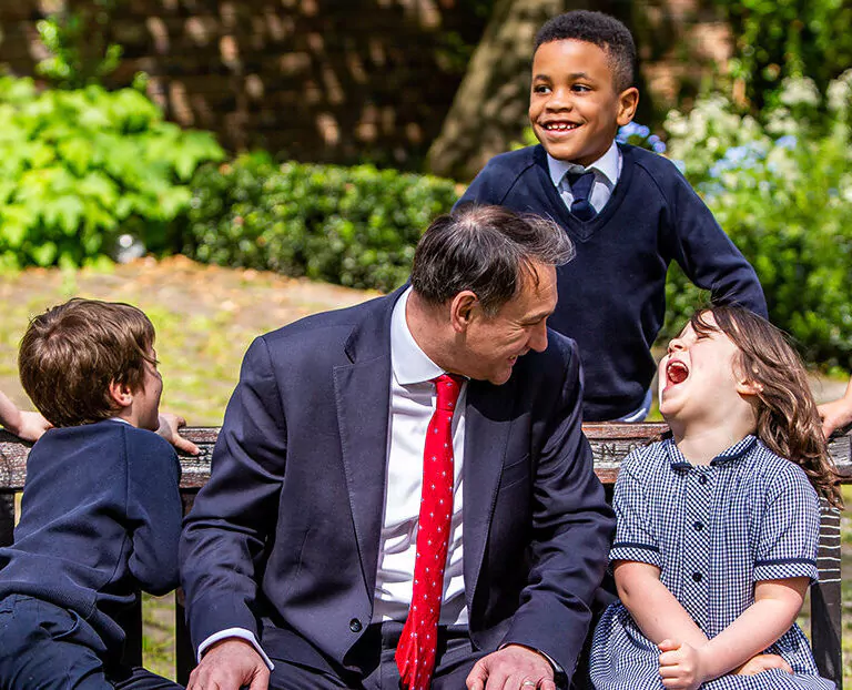 students surrounding a bench with the Head sat in the middle